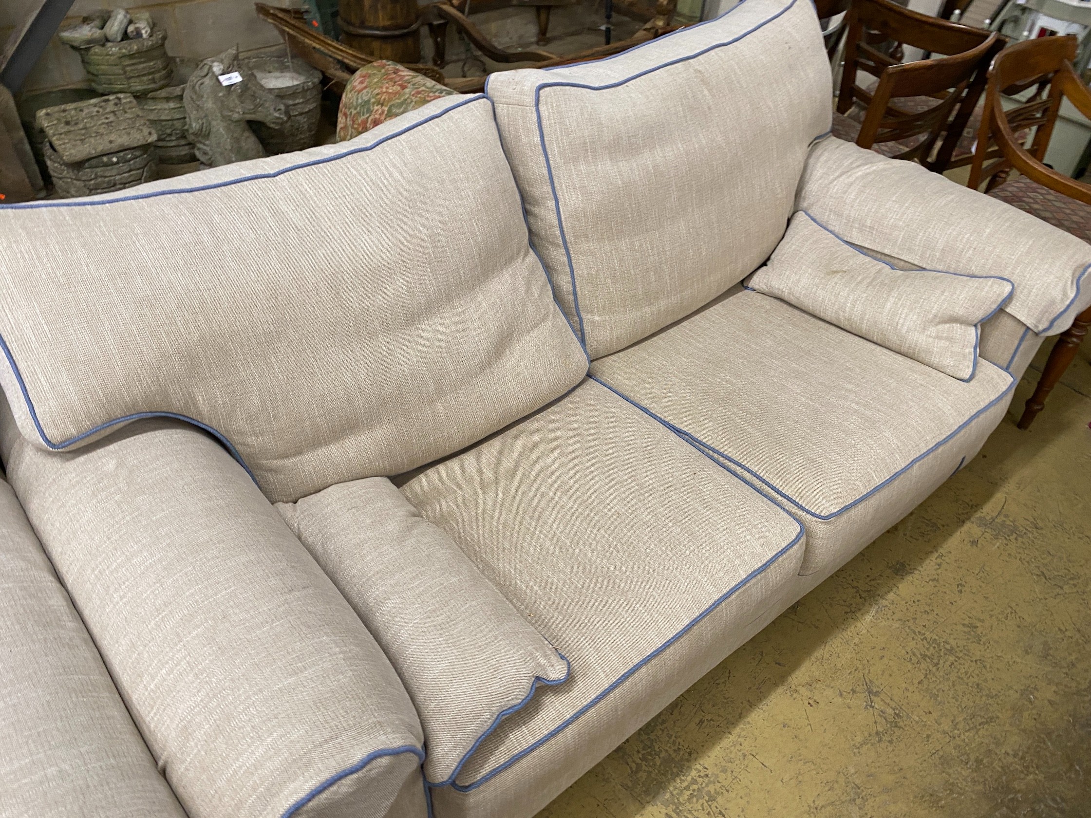 Two cream upholstered settees, with blue corded edging, larger length 200cm, depth 100cm, height 97cm